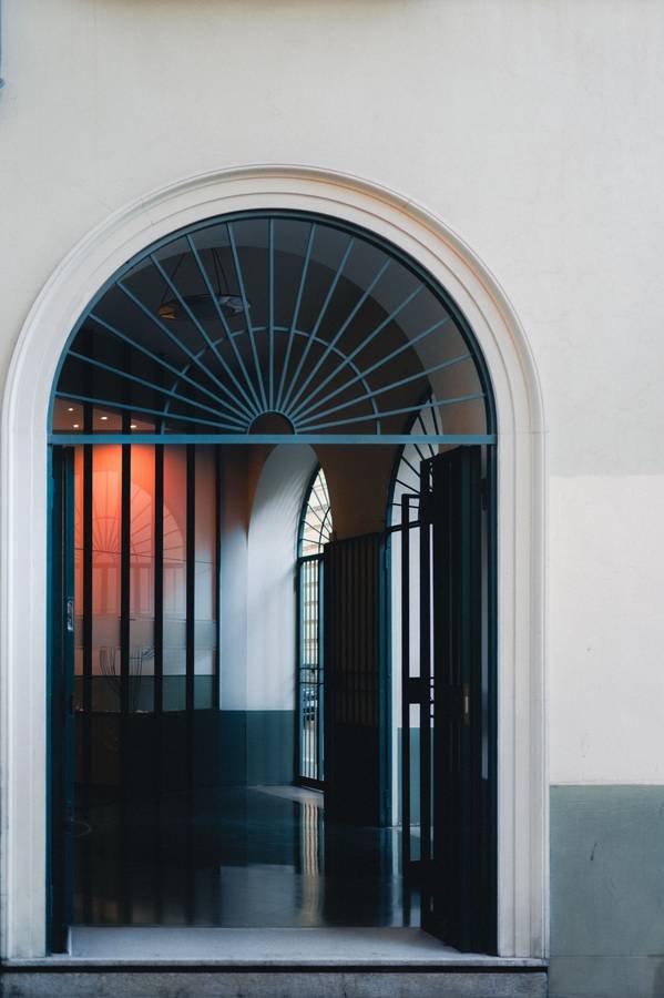An arched doorway with a fanlight, painted in soft white and deep teal